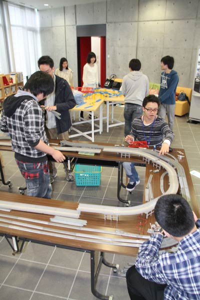 11日、燕市産業史料館で開かれている「捧武写真展～電鉄のある風景」でNゲージとプラレールの走行会に向けて設営を行う新潟大学鉄道研究部の部員