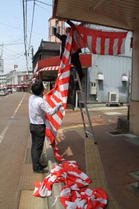 14日午前、一ノ木戸商店街で紅白幕を下げる店舗