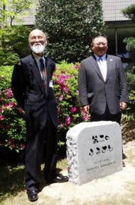 記念の石碑を前に発起人の佐竹紀さん(左)と医師の今野明さん