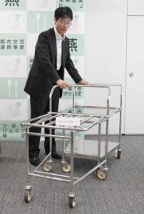 28日の定例記者会見で「学校給食用食器・備品の共同研究事業研究会」研究開発した新商品を紹介する鈴木燕市長、写真は学校給食用スタッキングカート
