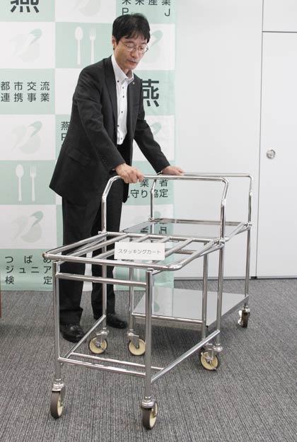 28日の定例記者会見で「学校給食用食器・備品の共同研究事業研究会」研究開発した新商品を紹介する鈴木燕市長、写真は学校給食用スタッキングカート
