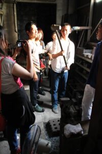 「プレ工場の祭典」で日野浦刃物工房を見学する芸大の学生