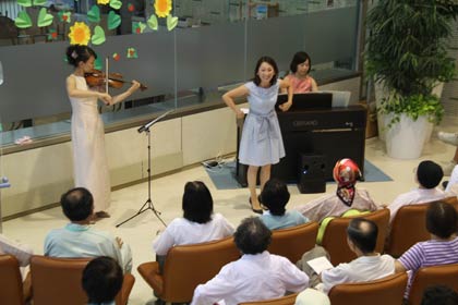 観客と一緒に体も動かして歌う、左からバイオリンの藤田さん、歌の猿丸さん、ピアノの小林さん