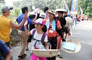 7日スタートした「寺小屋つばさ100km徒歩の旅」、1日目の宿泊先の三条市グリーンスポーツセンターに到着し、実行委員とハイタッチする子どもたちや学生スタッフ