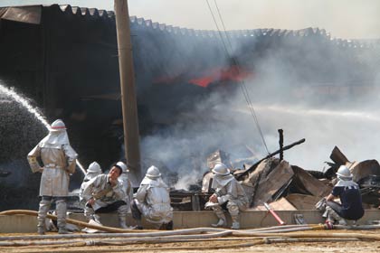 午前10時現在、建物奥には赤い炎が見えるが、消防士は熱中症にも気をつけて休憩をとりながら消火作業を続ける