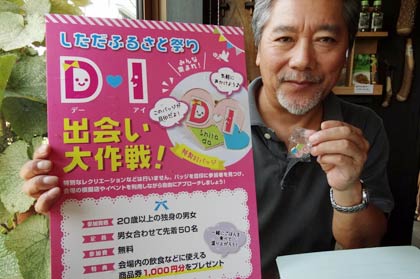 24日の「しただふるさと祭り～雨生の大蛇祭」で行う「しただふるさと祭りDI（出会い）大作戦」のポスターとDIバッジを手にしただふるさと祭り実行委員会の山田宏高企画委員長