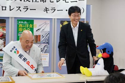 ぬいぐるみを机の上に座らせてつば九郎からカンさんへのメッセージを鈴木市長が代読