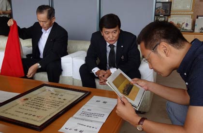 首相官邸での記念写真に見入る国定市長