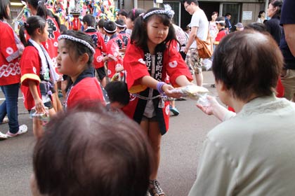 お年寄りからほうびの菓子を受け取る