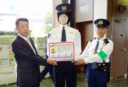 三条信用金庫本店に設置した署員手作りの「お巡りさん等身大人形」の贈呈式、左から同金庫の小浦方常務理事、「のんちゃん」、製作者の野沢巡査部長