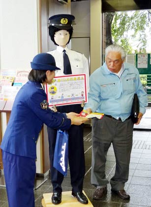 「のんちゃん」が立つロビーで来店客に特殊詐欺被害防止を呼びかけるちらしを配布