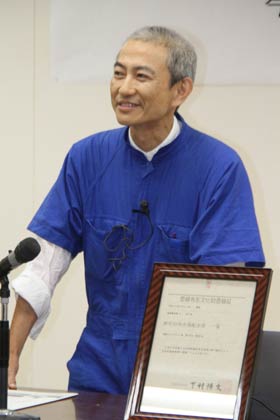  登録有形文化財登録証を前に記念講演を行う平山教授