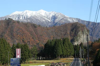 27日午後、青空の下に冠雪が白銀に輝く粟ヶ岳と紅葉をまとった八木ヶ鼻