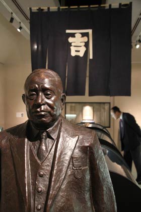  第八代捧吉右エ門の胸像と屋号の“かなきち”を染め抜いたのれん