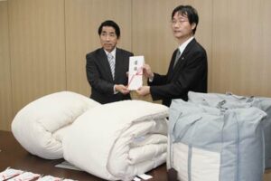 チャリティーバーゲンの収益金で燕市内の福祉施設に羽毛掛け布団20枚を寄付した山下家具店の山下社長(左)と目録を受けた鈴木市長