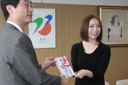 鈴木市長に10万円を包んだのし袋を手渡す本宮宏美さん