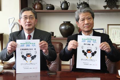  燕市内の学校給食用スプーンを共同開発して燕東小で上原教育長から感謝状を受け取った広瀬金属の広瀬社長(左)とニシムラの西村社長(右)