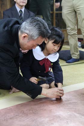 手を取って園児の打ち始めを指導する玉川社長