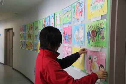 通路の壁に園児絵画展の作品を張って準備