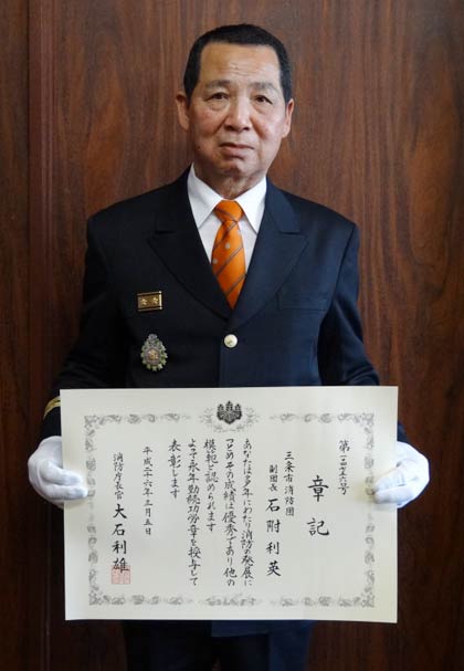 平成25年度消防庁長官定例表彰の永年勤続功労章を受章し、章記（表彰状）の伝達を受けた三条市消防団の石附利英副団長