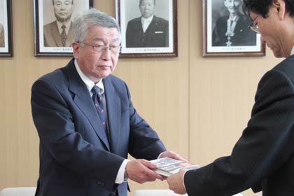 相場商事株式会社が出版した『満鮮産業視察団日誌』10冊を鈴木燕市長に手渡す相場社長