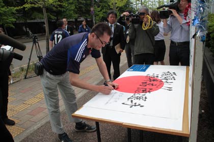 日の丸に応援のメッセージを書く後援会会員
