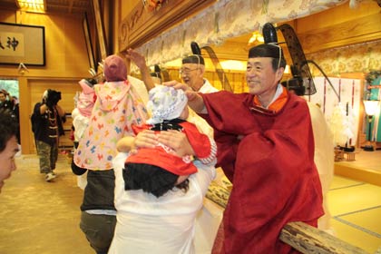  拝殿に上がった子どもの頭をなでる藤崎宮司や神官