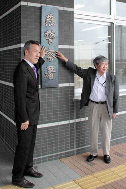 修繕されて再び燕署の正面玄関に掲げられた署看板の前で、書著感謝状を受けた玉川堂の玉川社長(左)と51年前に署看板が寄贈された当時、燕署に勤務していた吉田さん(右)