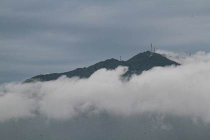 10日朝、雲に包まれて山頂付近だけ顔を出す弥彦山