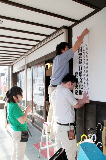「みんくる」が間借りしている旧新光屋米店店舗兼主屋の正面に国登録有形文化財の登録決定を祝う表示