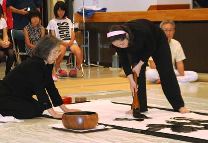 揮毫パフォーマンスを行う金澤翔子さんとサポートする母、素子さん