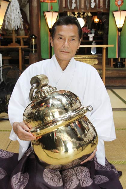 ピカピカに生まれ変わった鈴を抱く星野宮司