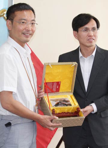 国定三条市長(左)を訪問してプレゼントの工芸品を手渡す中国駐新潟総領事館の何平総領事