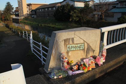 佐藤容疑者が心優ちゃんを西川に落としたと思われる中央橋の親柱には花や菓子が供えられた