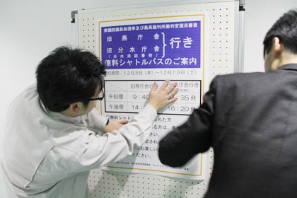 2日、燕市役所の期日前投票所にシャトルバスの案内の紙を張る市選管職員