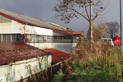  写真でいちばん高い屋根の手前4分の3が奧側にはがれ落ち、奥の4分の1の屋根にトタンが残る
