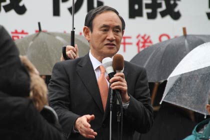  雨のなかで演説する菅氏