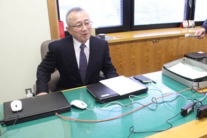 村長室は使わず職員と同じ執務室に置いた元は副村長用の村長のいすに座る小林村長