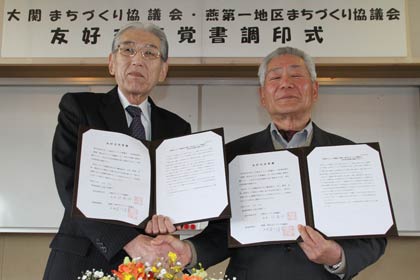 覚書に調印して握手する燕第一地区まち協の笹川会長（左）と福井県坂井市の大関まち協の伊藤会長