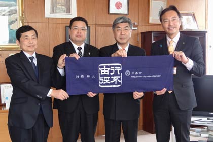 国定三条市長を表敬訪問して21日の成人式で新成人に寄贈する諸橋轍次博士の座右の銘「行不由径」をデザインした手ぬぐいを披露したNPO三条市成人式サポート協会、左から渡辺副代表、大野副代表、松永代表、国定市長