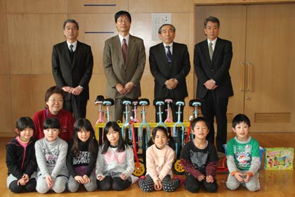  「しんくみピーターパン募金」から燕市の小中川児童館に20万円相当の一輪車9台とそのスタンド1台、二輪スクーター2台、ブロック玩具1セットを寄付して記念撮影