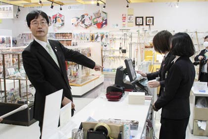 2日、免税店としてリニューアルオープンした燕三条地場産業振興センター物産館でオープンイベント、免税の会計を体験する同センター理事長の鈴木燕市長