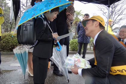 「新入学(園)児を守る交通安全週間」にあわせて三条市立西鱈田小学校の入口で行われた新一年生交通安全キャンペーンで国定市長から新一年生に啓発グッズ