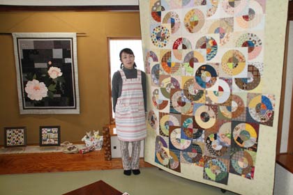  「手のぬくもり　心にゆとり展」を開いている分水の寿司店「惣六」で3畳の大きさのキルト作品のとなりでおかみの小柳さん