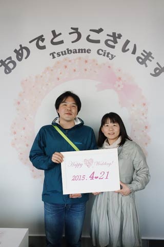 燕役所で婚姻届を提出してメッセージ入りの背景で記念写真を撮影するサービスを受けた夫婦