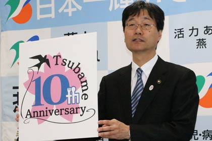 鈴木市長が定例記者会見、合併10周年記念ロゴマークを示す