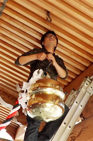 鈴を磨いた白井さんが鈴を拝殿に下げる