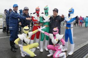 田んぼアートの田植えで一足早くお披露目したご当地ヒーロー「方言戦隊メテオレンジャー」、鈴木市長や来賓と一緒に記念撮影