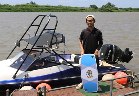 信濃川でウェイクボードを体験できる「モンキートラップ」の横山さん、シグネチャーモデルのボードを手に