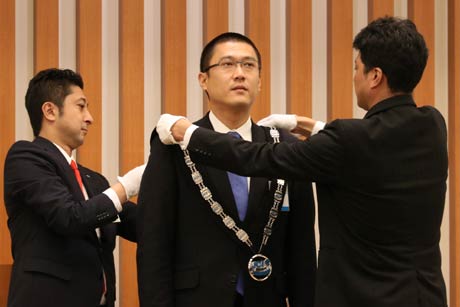  加藤直前理事長(左)と石黒理事長(右)からプレジデンシャルリーフを受ける相場さん(中央)